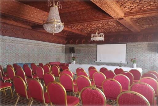 Sala de conferencias con filas de sillas y pantalla de proyección en el hotel Chellah