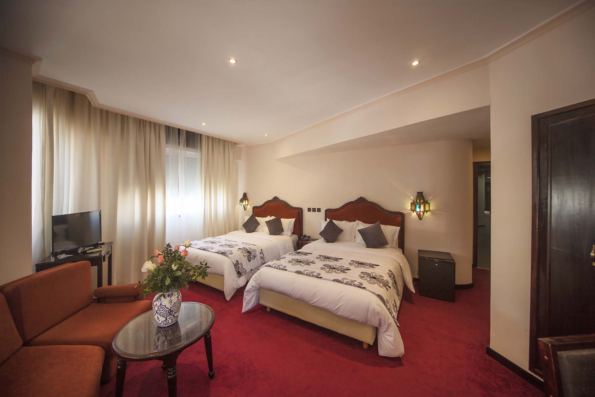 Habitación con dos camas, zona de estar y televisión