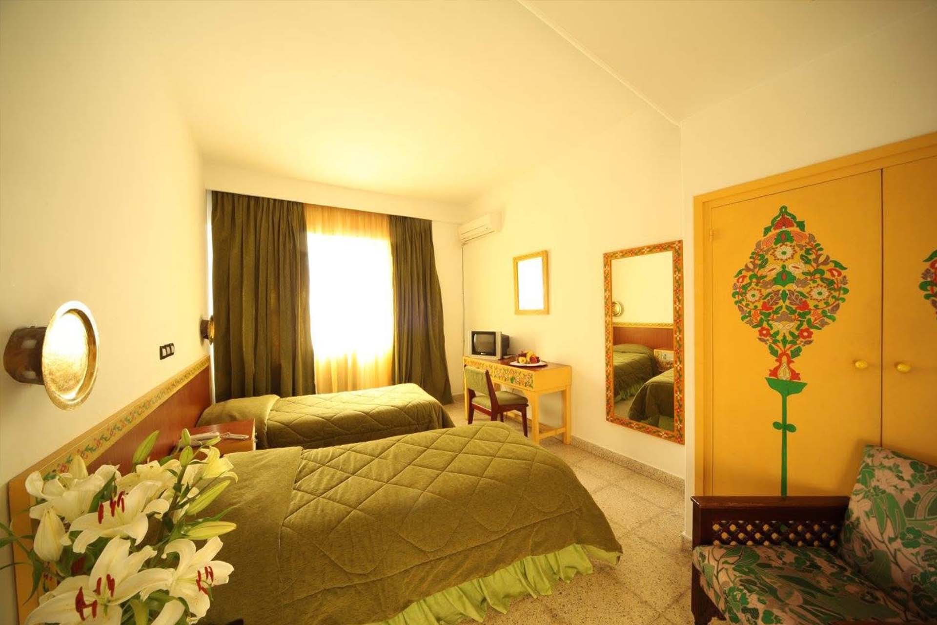 Habitación con dos camas, colchas verdes y armario pintado